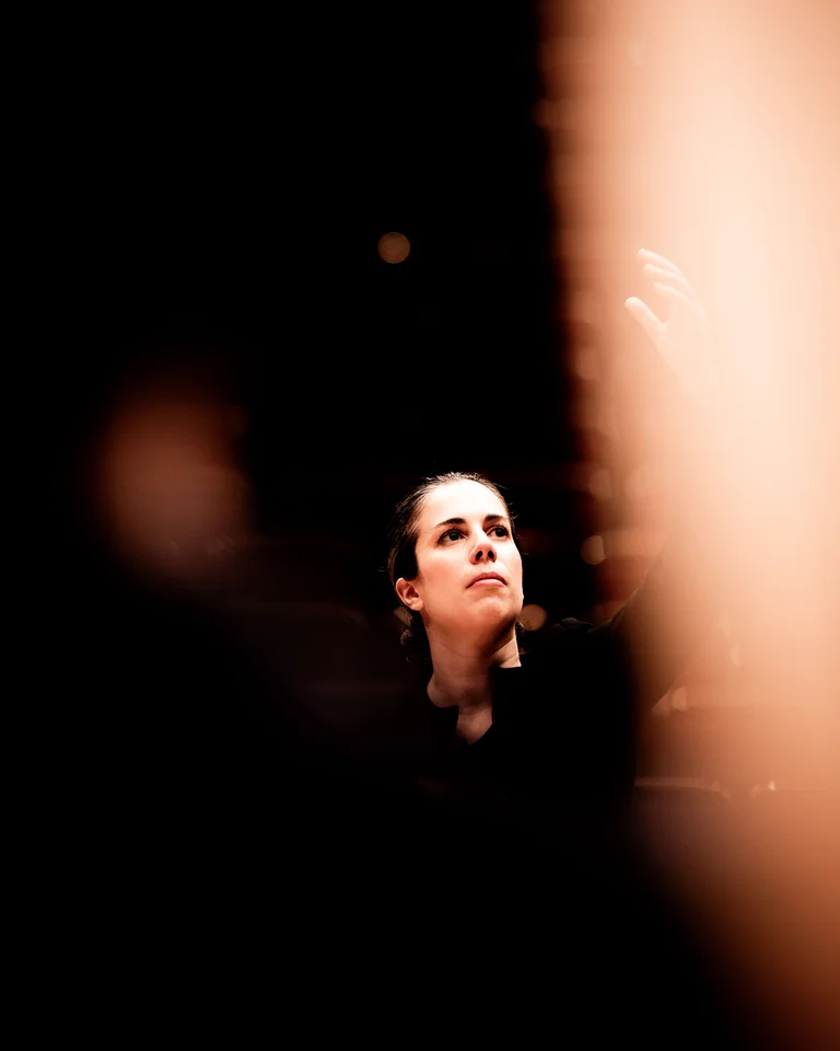 Eine Person schaut konzentriert in die Ferne. Das Bild hat einen verschwommenen, künstlerischen Vordergrund und dunklen Hintergrund.