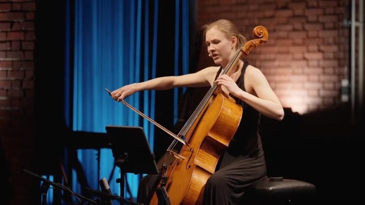 Valerie Fritz spielt Cello auf einer Bühne mit blauem Vorhang im Hintergrund.