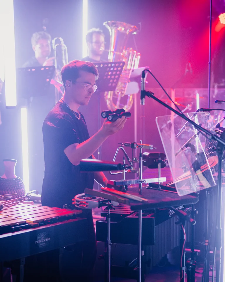 Members of the treppenhausorchester play in an atmospherically lit room, surrounded by instruments and microphones. The atmosphere feels dynamic and creative.