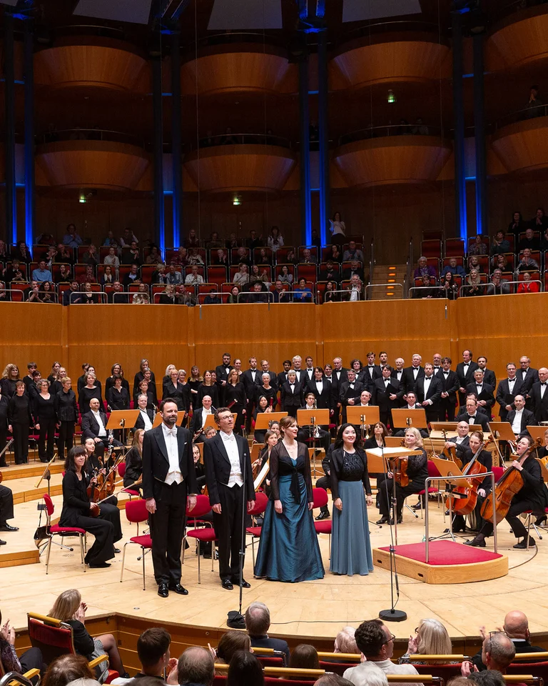 Ein großes Orchester und Chor (Concert-Chor Concordia Hürth) treten in der Kölner Philharmonie auf. Musiker und Sänger stehen auf der Bühne.