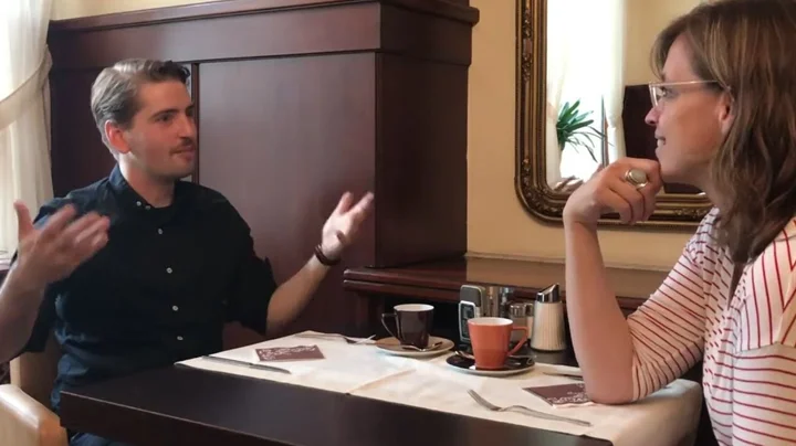 Pablo Held and Anke Steinbeck from Jazzfest Bonn are sitting at a table in a café, engaged in a lively conversation.