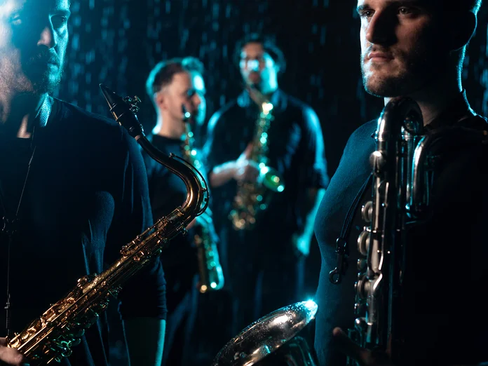 Vier Musiker (SIGNUM Quartett) spielen Saxophon in gedämpfter Beleuchtung, was eine stimmungsvolle und intime Atmosphäre schafft.