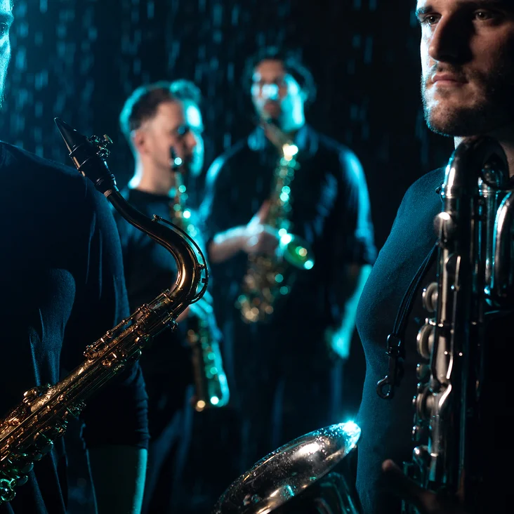 Vier Musiker (SIGNUM Quartett) spielen Saxophon in gedämpfter Beleuchtung, was eine stimmungsvolle und intime Atmosphäre schafft.