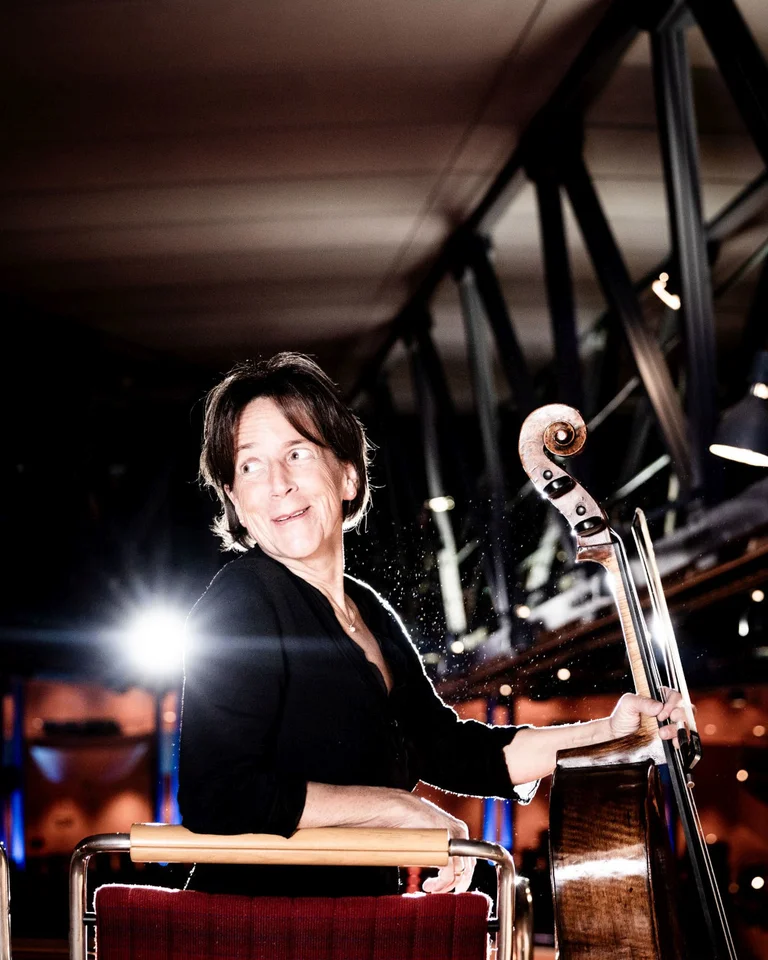 Eine Musikerin spielt Kontrabass in einem Konzertsaal, beleuchtet von Scheinwerfern. Die Atmosphäre wirkt feierlich und konzentriert.