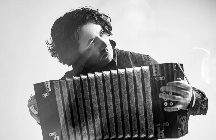 Goran Stevanovich spielt Akkordeon, vertieft in seine Darbietung. Das Schwarzweiß-Foto betont stimmungsvolle Lichteffekte.