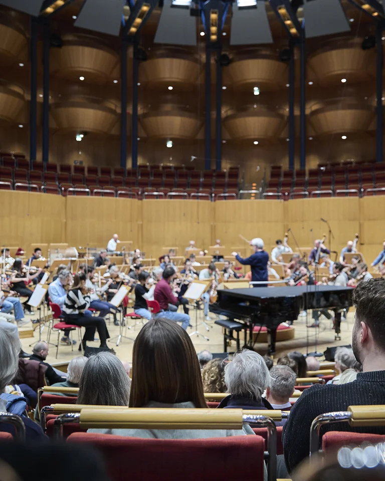 Ein Orchester spielt in der Kölner Philharmonie vor einem Publikum. Der Dirigent steht vor den Musikern.