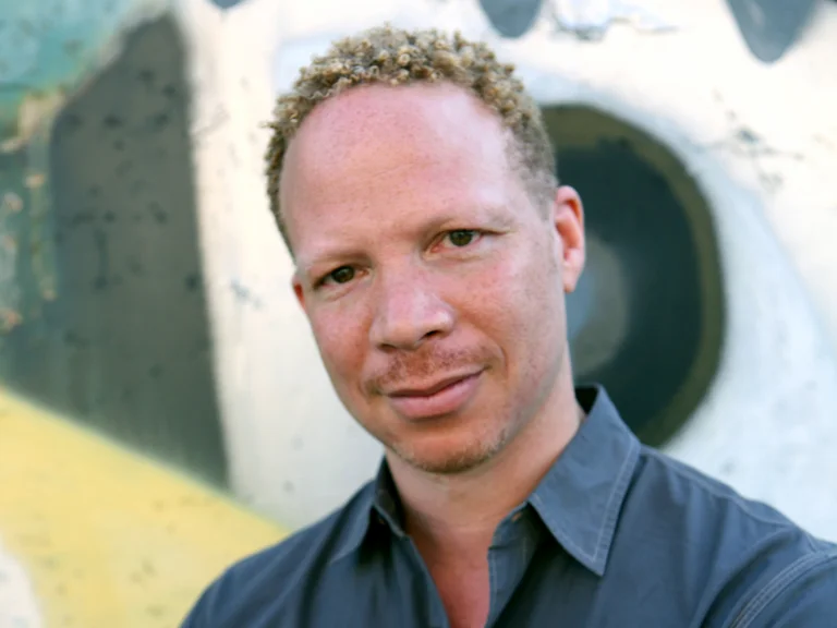 Ein Mann (Craig Taborn) steht vor einer grafischen Wand mit abstrakten Mustern. Sie trägt ein dunkelblaues Hemd und schaut direkt in die Kamera.