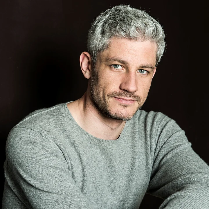 Edwin Crossley-Mercer poses in front of a dark background.