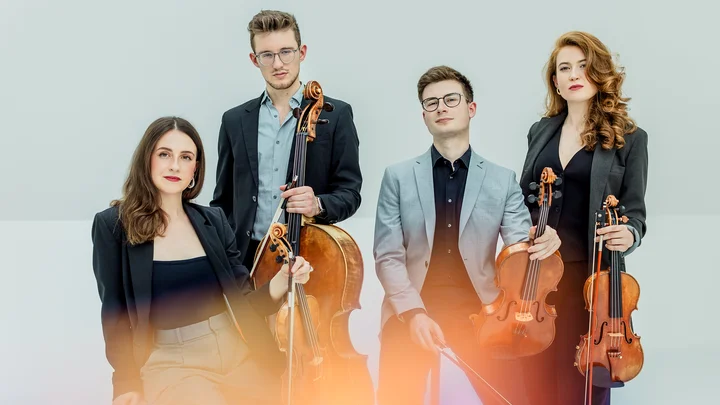 Ein Streichquartett (Javus Quartett) posiert mit ihren Instrumenten: zwei Geigen, eine Bratsche und ein Cello, in eleganter Kleidung.