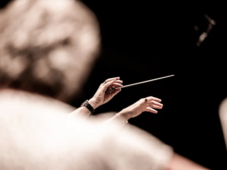 Yannick Nézet-Séguin mit dem Chamber Orchestra of Europe: Ein Dirigent schwenkt den Taktstock mit elegantem Schwung vor unscharfem Hintergrund. Der Moment einfängt die Kunst der Leitung.