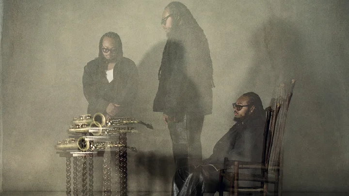 Verschwommene Aufnahme von einem Mann (Immanuel Wilkins) mit Saxophonen, in einem kunstvollen, geheimnisvollen Setting. Eine faszinierende Darstellung von Jazzästhetik.