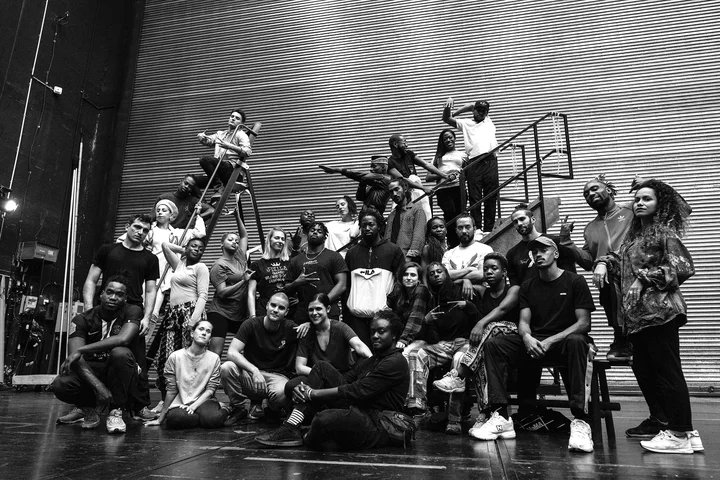 The members of Structure Rualité pose casually on a theater stage. The scene conveys a creative and dynamic atmosphere.