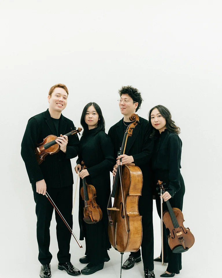 Vier Musiker (Leonkoro Quartett) in schwarzer Kleidung posieren mit Streichinstrumenten. Zwei spielen Violinen, einer trägt ein Cello und einer eine Viola.