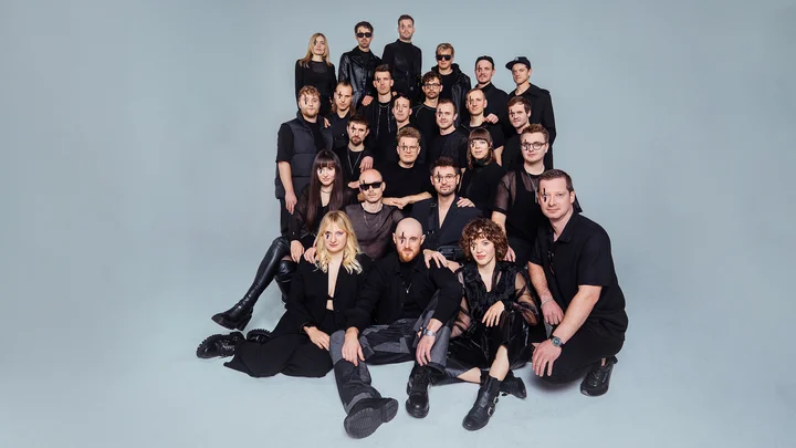 Eine große Gruppe von Menschen in schwarzer Kleidung (Jazzrausch Bigband) posiert in mehreren Reihen vor einem neutralen Hintergrund.