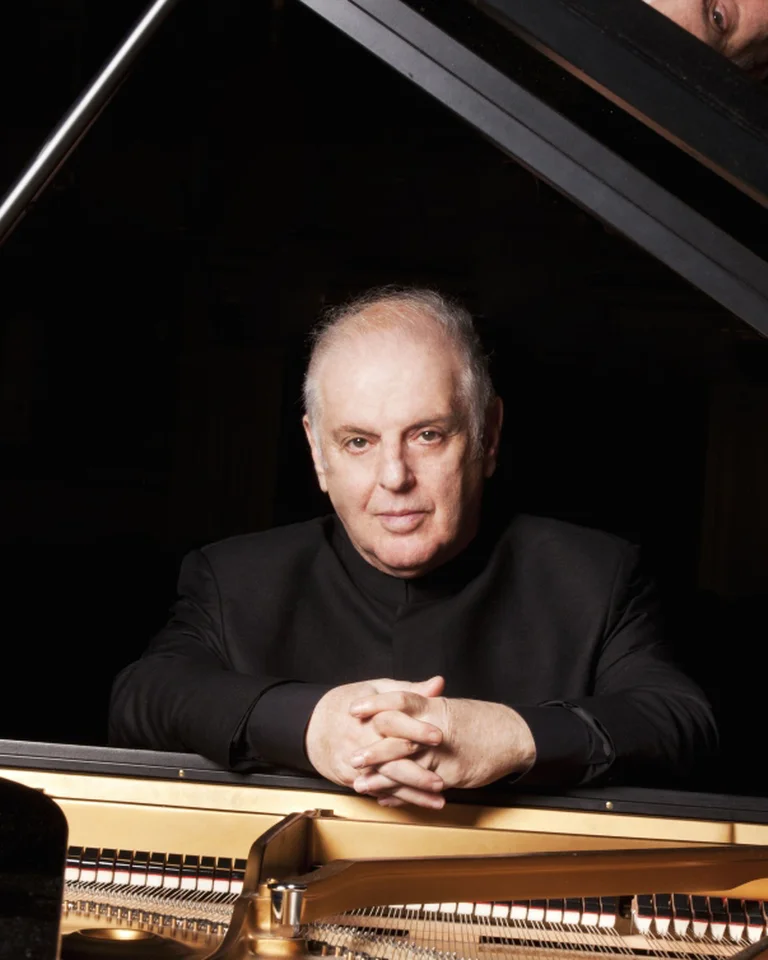 Eine Person sitzt an einem Flügel und schaut direkt in die Kamera. Ruhige, konzentrierte Atmosphäre um das Klavier.