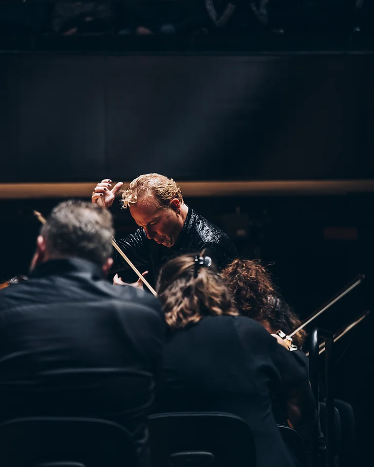 Ein Dirigent leitet ein konzentriertes Orchester (Yannick Nézet-Séguin mit dem Chamber Orchestra of Europe) in einem Konzertsaal, während das Publikum aufmerksam zuhört.