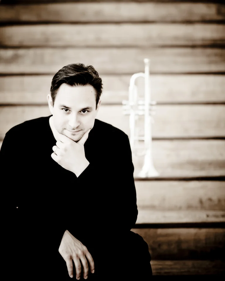 Ein Mann sitzt auf einer Treppe, den Kopf auf die Hand gestützt, mit einer Trompete hinter ihm.