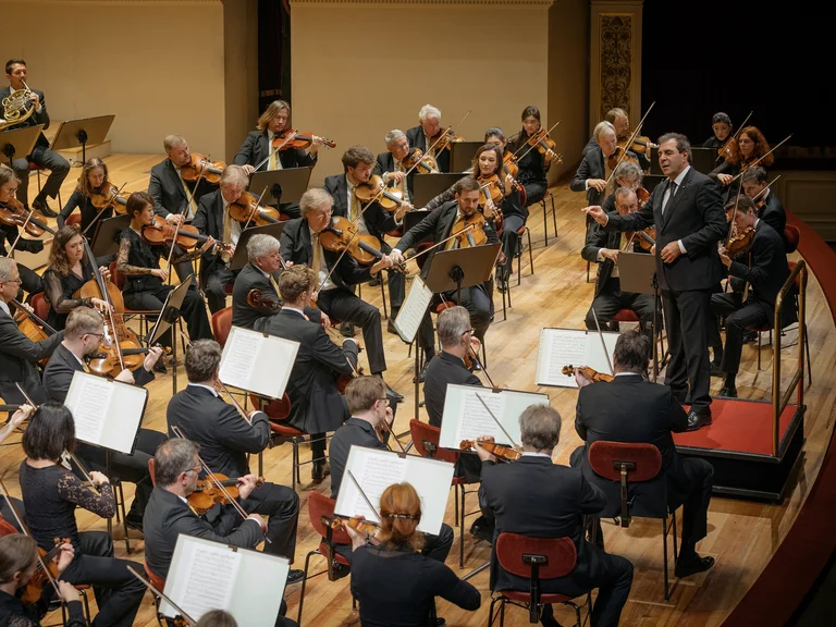 Daniele Gatti mit Sächsische Staatskapelle Dresden: Ein Orchester spielt auf einer Bühne. Der Dirigent leitet die Musiker, die eine Vielzahl von Musikinstrumenten spielen.