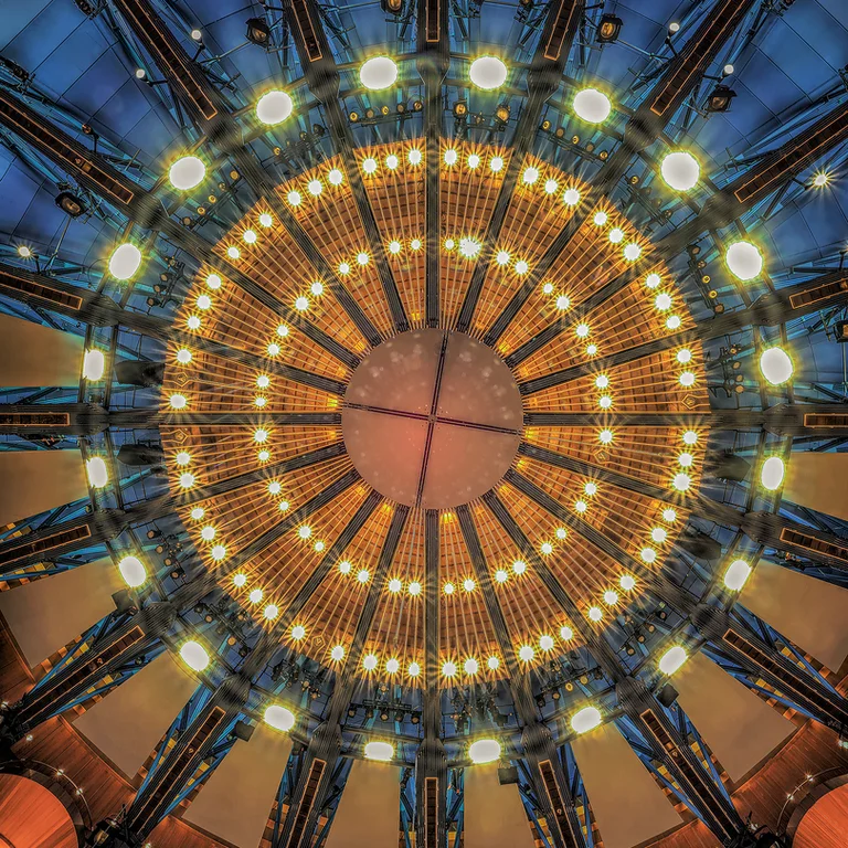 The ceiling of the Kölner Philharmonie with a radial pattern of lights, shining in warm gold and blue tones.