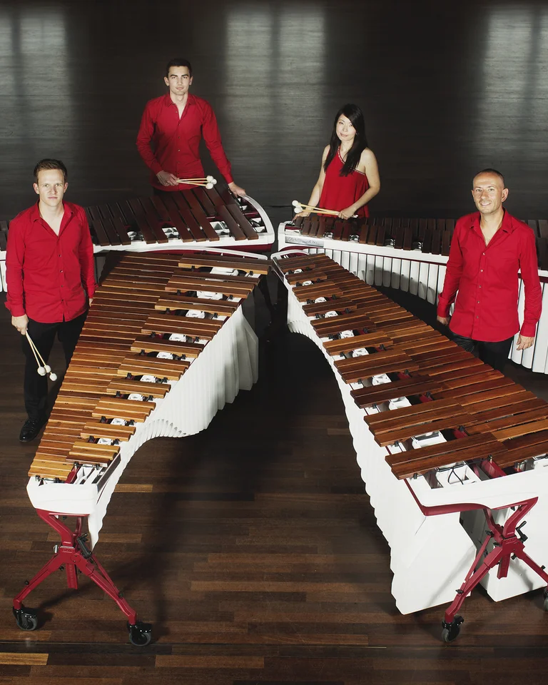 Die vier Mitglieder des Wave Quartet stehen in einem eleganten Raum mit Holzfußboden an ihren Marimbas.